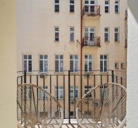 A balcony with a view of the courtyard, part of a 4-room apartment, offers comfortable seating.