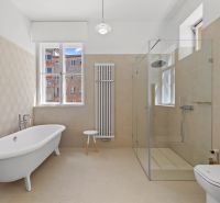 A bathroom with a freestanding bathtub, a glass-enclosed shower, and a view of the surrounding buildings.