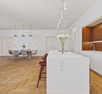 Spacious kitchen in a 4-room apartment with an island and wooden decor flooring.
