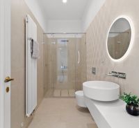 Bathroom in a 4-room apartment with a glass shower enclosure and a round illuminated mirror.