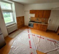 A kitchen in a family house with a wooden floor decor, kitchen unit, and a large window.