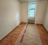 The interior of a room in a family house with a wood-patterned floor and a radiator.