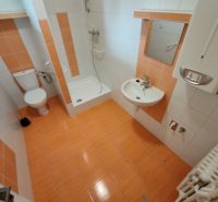 A bathroom in a family house with orange and white tiles and a shower corner.