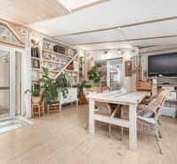Interior of a family house with a wooden decor floor, rattan chairs, and houseplants.