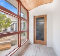 A glazed corridor in a family house with a view of the garden, floor with wooden decor.