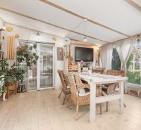 Interior of a family house with rattan furniture, decorative plants, and a floor with a wooden decor.