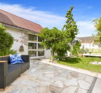 The garden of a family house on Robotnícka Street in Tomášov with a rattan sofa and greenery.