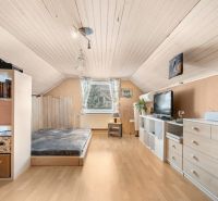 Attic room of a family house with a bed, dresser, and shelves, floor with wooden decor.