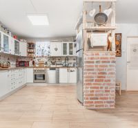 A kitchen in a family house with brick walls and a wooden decor floor.