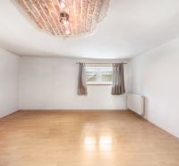 A room in a family house with a wooden decor floor, a radiator, and a small window.