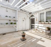 The courtyard of the family house on Robotnícka Street in Tomášov with a terrace, flower pots, and seating.