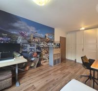 A room with colorful wallpaper and a wooden decor floor in a two-room apartment.