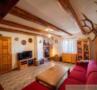 Living room of a family house with wooden beams and a fireplace, comfortable seating.