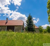 A family house in Budiná surrounded by greenery and blue skies.