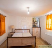 Bedroom in a family house with wooden furniture and orange curtains.