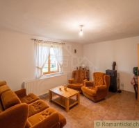 A living room in a family house with orange furniture, tiles, and wooden doors.