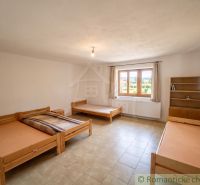 A room in a family house with multiple beds, a window, and a shelf.