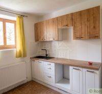A kitchen with wooden cabinets, yellow curtains, and white walls in a family house.