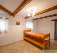 Interior of a family house with wooden beams, bunk beds, and tiled floor.