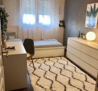 Children's room with a desk, carpet, and wooden decor flooring in a family house.