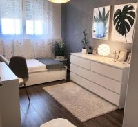 A room in a family house with a wooden decor floor, artistic paintings, and decorative flowers.