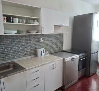 A kitchen in a 3-room apartment with white cabinets and gray tiles.