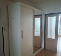 A wardrobe with a mirror in a 3-room apartment with a wooden decor floor.