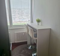 A kitchen in a 3-room apartment with white furniture, a window with blinds, and a flower.