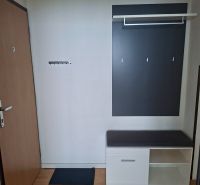 The entrance hall of a 3-room apartment with a wardrobe, a bench, and a wooden decor floor.