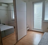 A bedroom in a three-room apartment with a large wardrobe and a wooden decor floor.