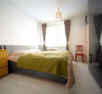 A bright bedroom in a three-room apartment with a comfortable bed and wooden furniture.