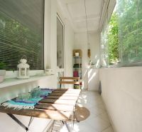 Balcony in a 3-room apartment with a wooden table and greenery in the background.