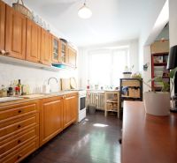 A kitchen in a 3-room apartment with wooden cabinets and a floor with a wooden decor.