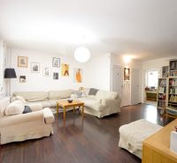 Living room in a 3-room apartment with a sofa, bookshelf, and wooden decor flooring.