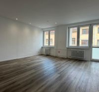 A spacious living area in a three-room apartment with a wooden decor floor.