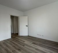 A room with white walls and a wooden decor floor in a 3-room apartment.