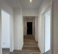 A hallway in a 3-room apartment with a wooden decor floor and white walls.