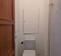 A toilet in a 2-room apartment with simple furnishings and tiles.