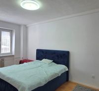 A bedroom with a bed, a work desk, and a floor with a wooden decor in a two-room apartment.