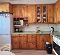 A kitchen in a 2-room apartment with a light wood decor and modern appliances.