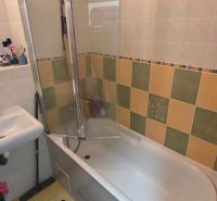 Bathroom in a 2-room apartment with a bathtub and colorful wall tiles.