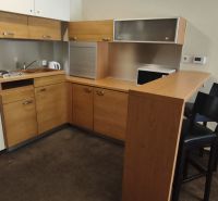 A kitchen in a holiday apartment with wooden cabinets and a bar counter.