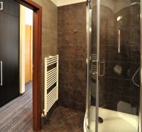 Bathroom in a holiday apartment with dark tiles and a shower corner.
