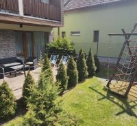 The courtyard of a recreational apartment in Demänová with a terrace, a playground, and green conifers.