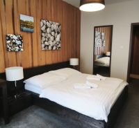 Bedroom with a double bed and wooden paneling in a Holiday Apartment.