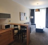 Interior of a vacation apartment with a sofa, microwave, and a bar table with two chairs.