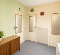 A hallway in a 3-room apartment with a wooden chest of drawers and a green wall.
