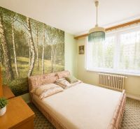 A bedroom in a 3-room apartment with natural wallpaper and simple furniture.