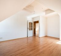 A room in a family house with white walls and a wooden-patterned floor.
