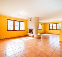 A spacious room with a fireplace and terracotta tiles in a family house.